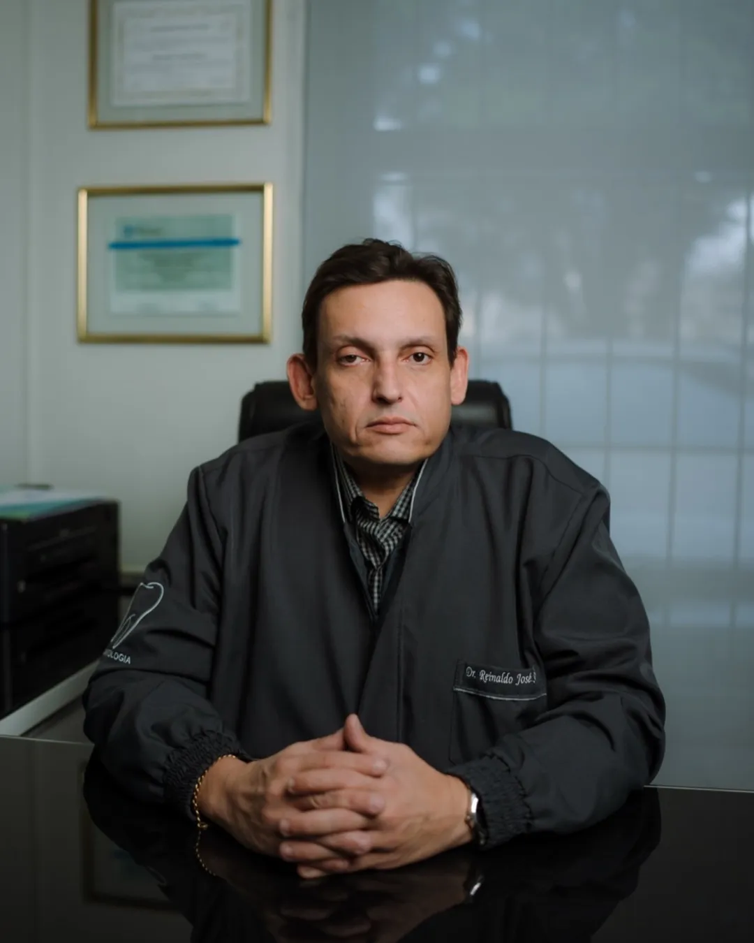 Dr. Reinaldo José Seco, cirurgião-dentista, em seu consultório em Maringá, com os diplomas ao fundo.