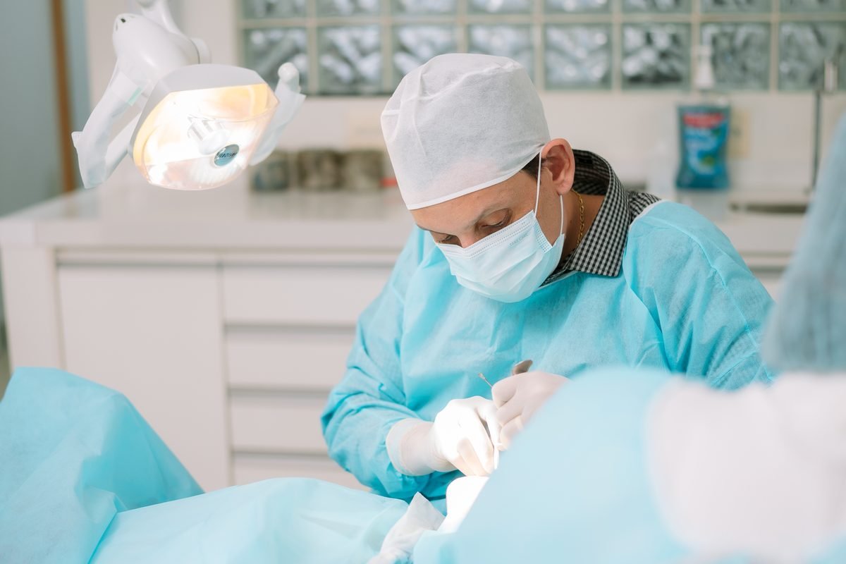 Procedimento cirúrgico odontológico em andamento, com campo operatório montado e o paciente sem identificação.